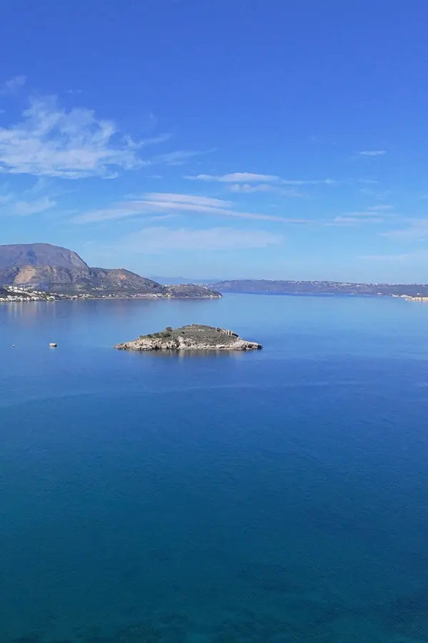 Coastal panorama of Almyrida showcasing the lush green hills meeting the deep blue Aegean Sea.