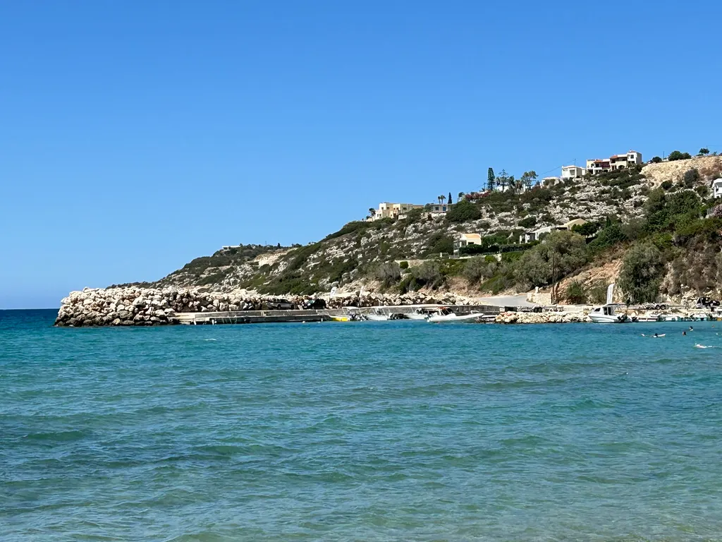 Coastal view of Almyrida featuring turquoise Aegean Sea waters and green Mediterranean foliage on Crete.