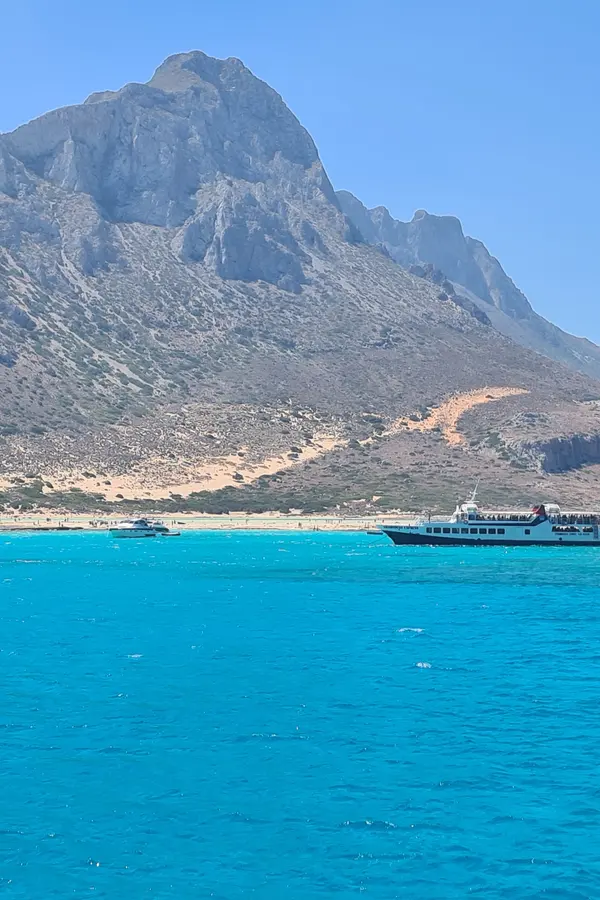 Emerald turquoise water meeting white sand and dramatic cliffs at Balos Lagoon, Crete.