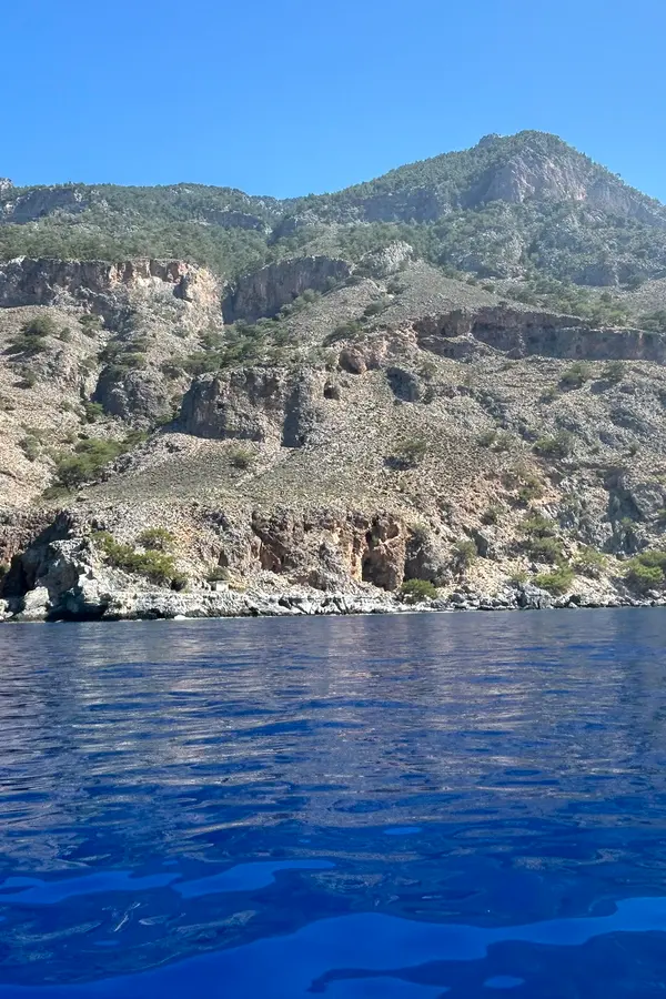 Rugged cliffs and crystalline blue waters at Domata, capturing the stunning southern Mediterranean coastline of Crete.