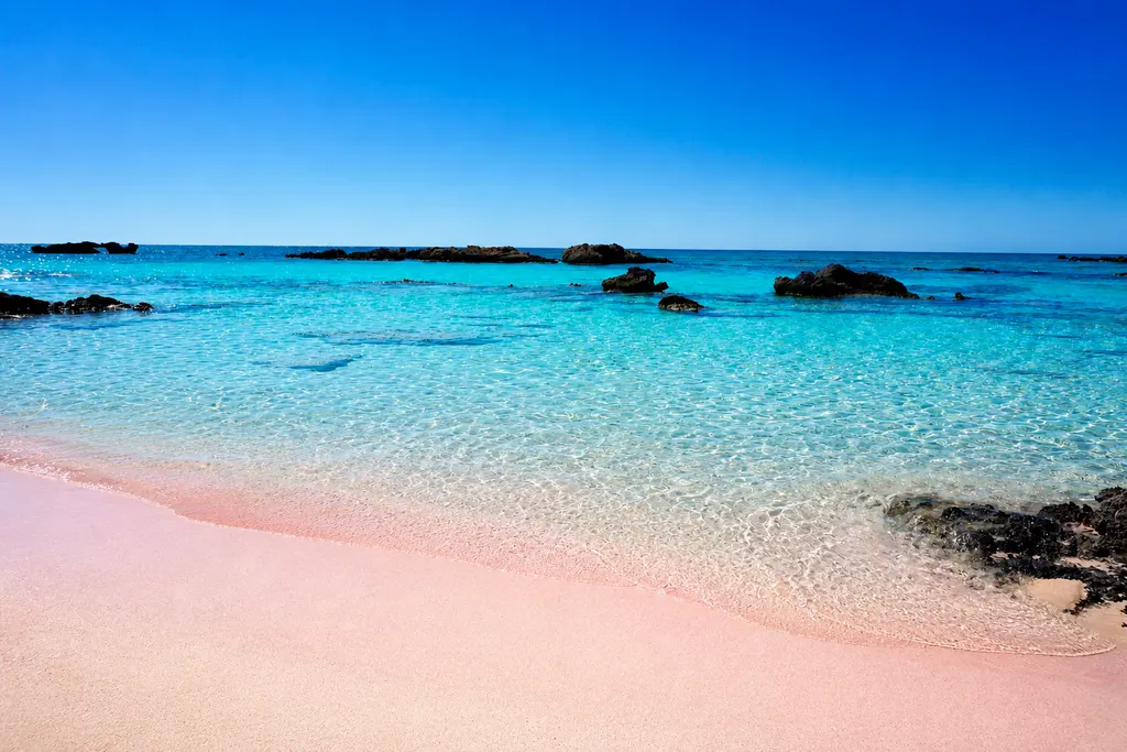 Pale pink sand and crystal-clear lagoon waters at Elafonissi beach, western Crete.