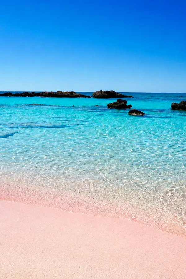 Pale pink sand and crystal-clear lagoon waters at Elafonissi beach, western Crete.