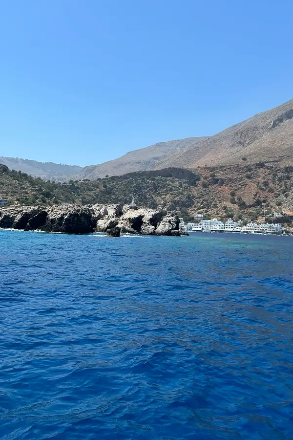 Whitewashed buildings and calm turquoise waters framing the beautiful fishing village of Loutro, Crete.