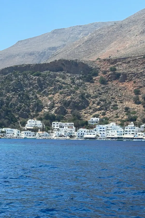 Loutro village nestled into the Mediterranean coastline, with clear turquoise waters embracing the charming harbor.