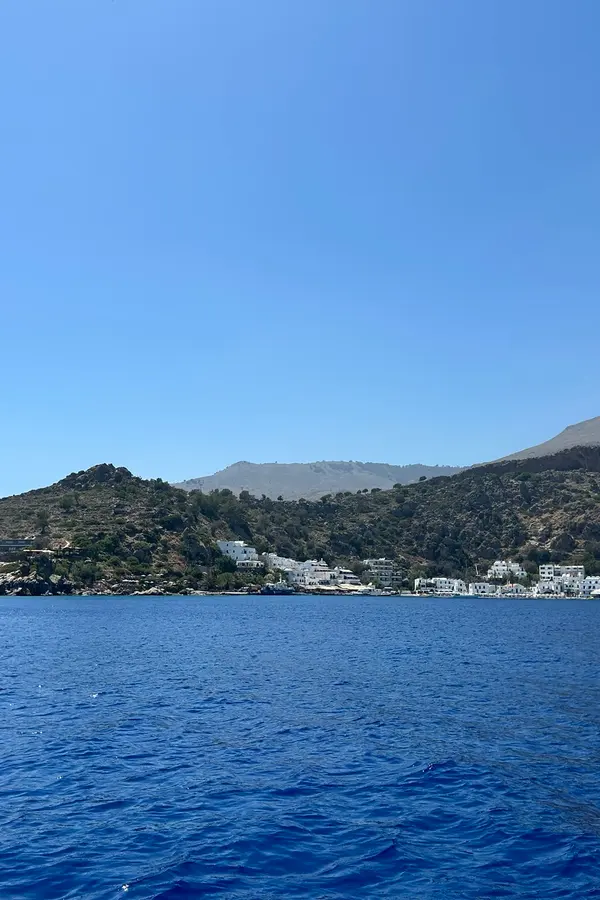 Picturesque village of Loutro nestled along the sheltered bay, facing deep Aegean blue waters.