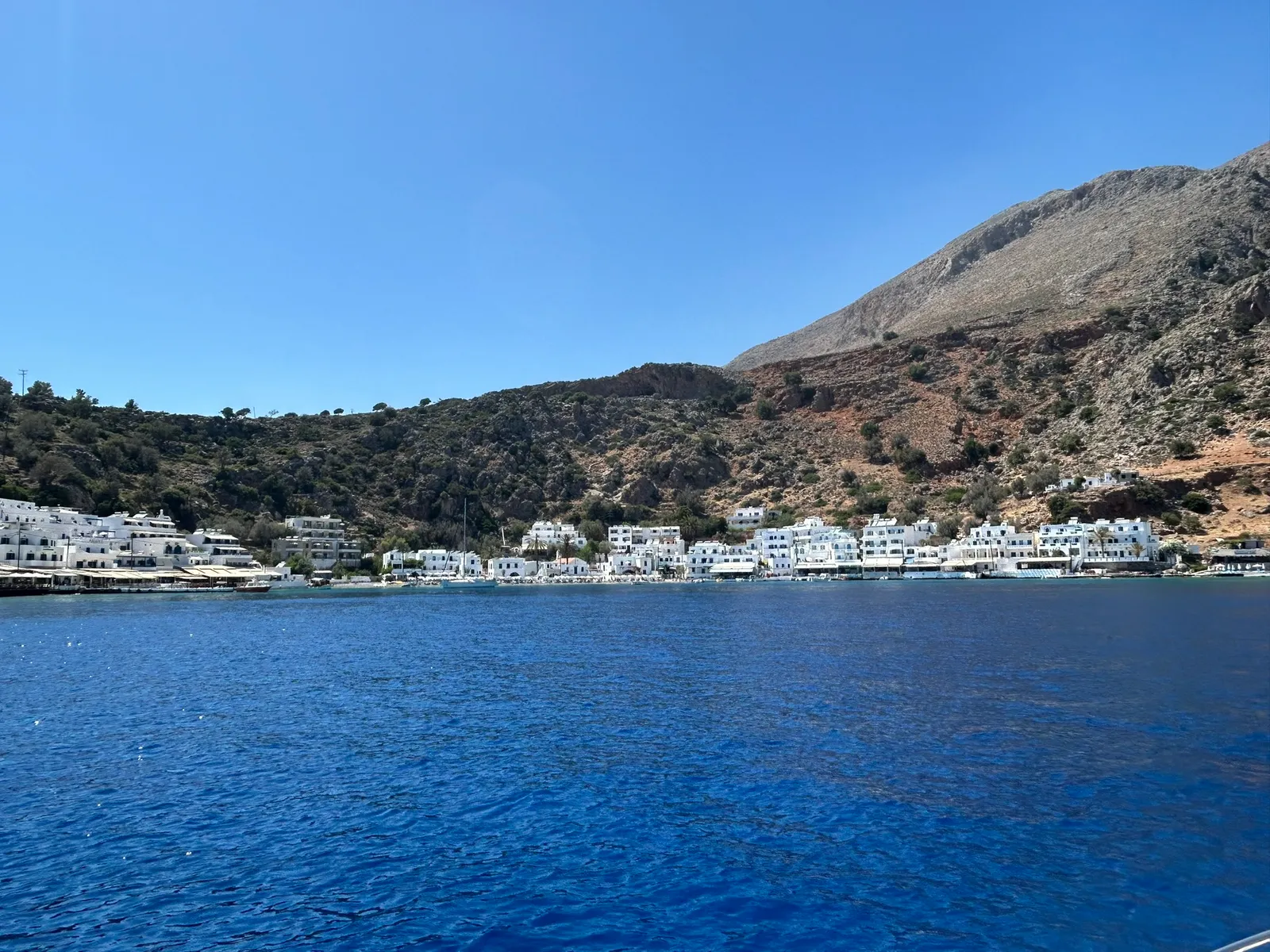 White-washed buildings of Loutro village nestled into the quiet bay of the Aegean Sea.