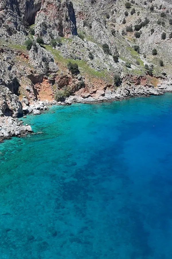 Clear blue Aegean Sea meeting the dramatic, rugged coastline at Ombrosgialos, Crete.
