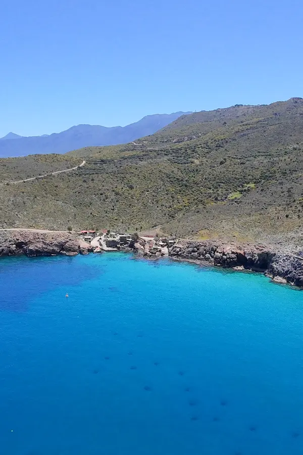 Steep, arid cliffs meeting deep blue waters at Ombrosgialos, showcasing the dramatic Cretan coastline.