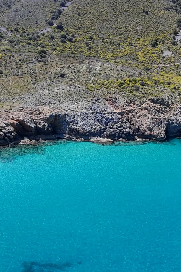 Dramatic coastal view of Ombrosgialos, showcasing turquoise waters meeting rugged cliffs on the Cretan coast.