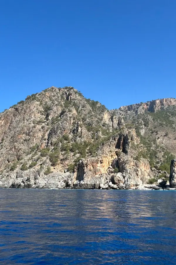 Dramatic rocky coastline at Tripiti, featuring sheer cliffs plunging into the deep blue Mediterranean Sea.