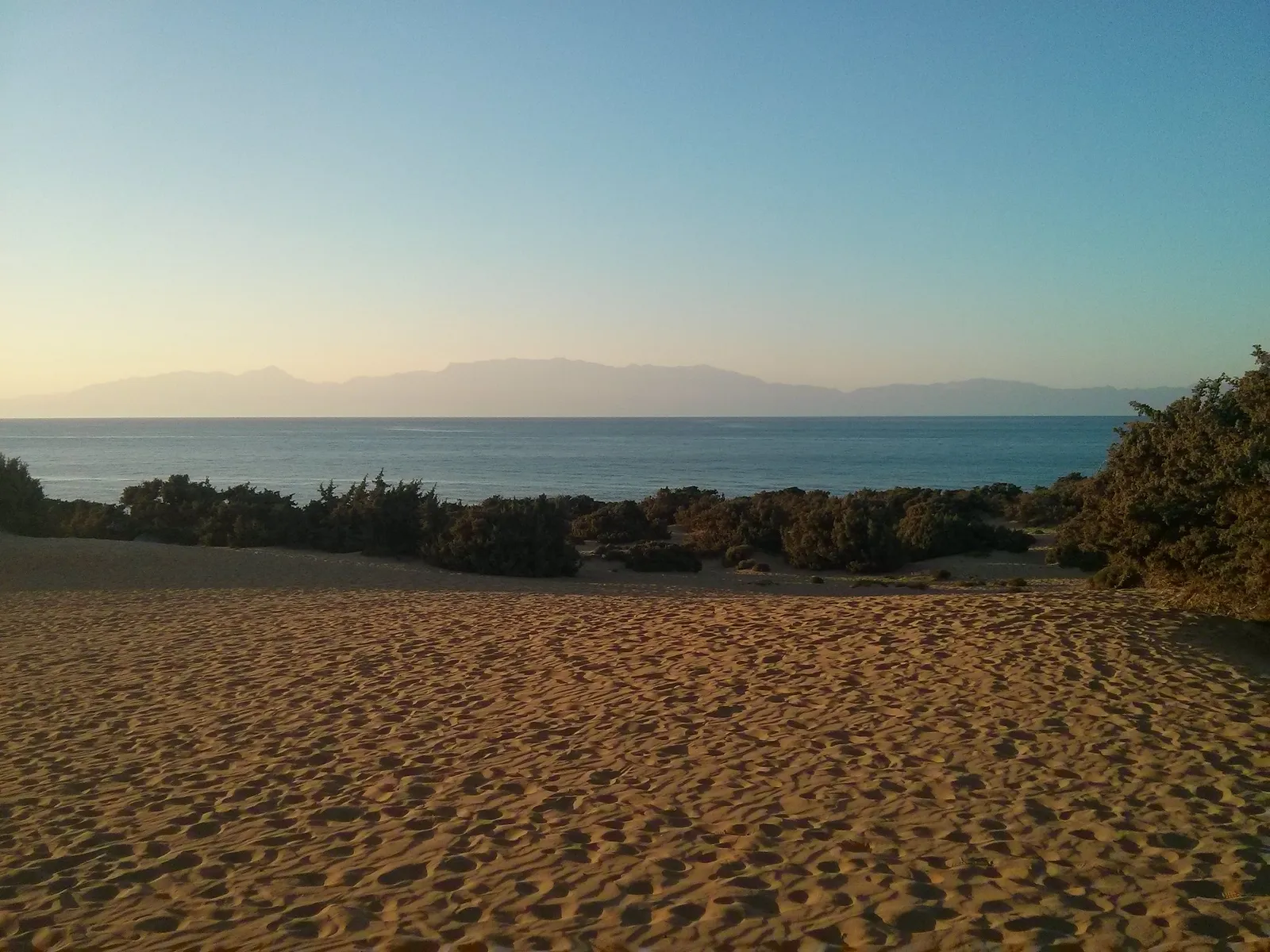 Clear blue sea meeting the white sandy beach on the rugged southern coast of Gavdos island.