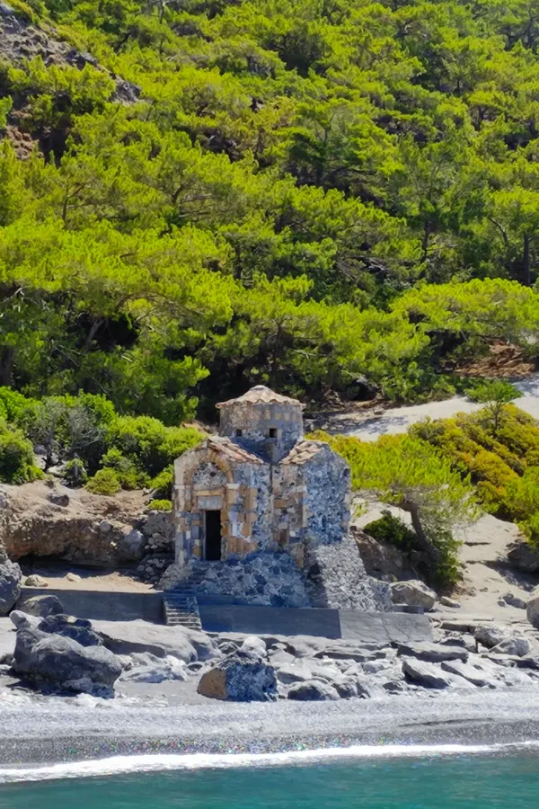 Crystal clear Aegean waters meeting the dry, rugged cliffs of the Cretan coast during a summer day trip.
